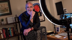 Arthur Brooks stands behind a chair in his office, smiling