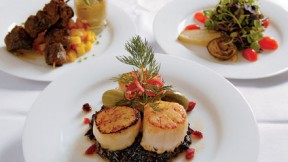 Scallops atop black sticky rice; behind, beef satay and baby greens