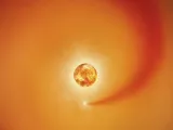 A glowing orange sun with a star and a trailing gas cloud in space.