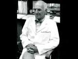 Black and white photo of Joseph Murray in a white lab coat sitting in an office.