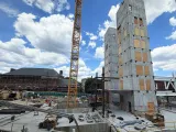 Construction site featuring tall concrete structures, cranes, and a blue sky with clouds.