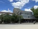 Modern building surrounded by trees and a blue sky with fluffy white clouds.