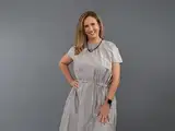 Woman wearing a silver dress stands confidently against a gray background.