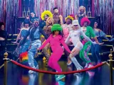 A vibrant group of dancers in colorful outfits poses on a stage with shiny decorations.