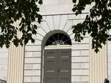 Historic building entrance featuring tall columns and a rounded arch doorway.