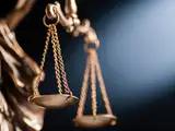 Close-up of a bronze scale symbolizing justice, with soft lighting in the background.