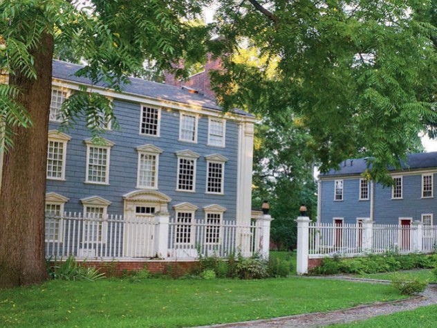 colonial-era blue house amid grass 