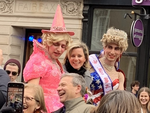 Elizabeth Banks looks at the camera as she rides in a convertible with two members of the Hasty Pudding Theatricals.