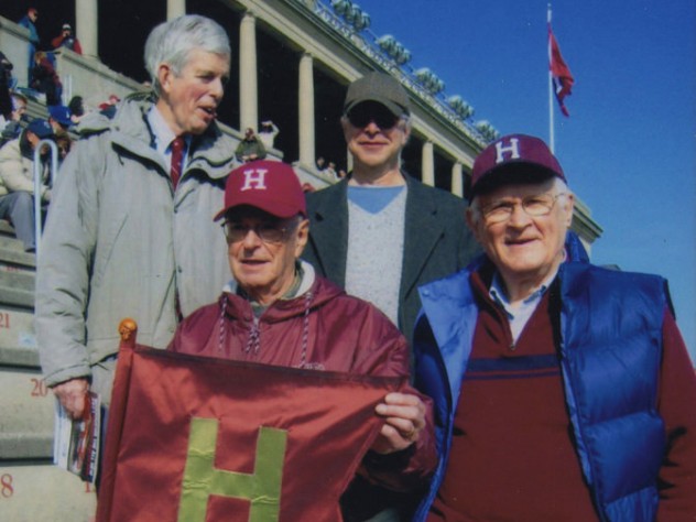 Alumnus Paul Lee ’46 carries the (replica) Little Red Flag at the 2012 Harvard-Yale game. Steve Goodhue ’51 is beside him; Spencer Ervin ’54 and Jeff Lee ’74 stand behind.