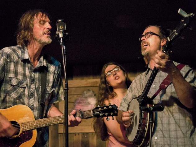 A bluegrass guitarist, banjoist, and singer perform on stage