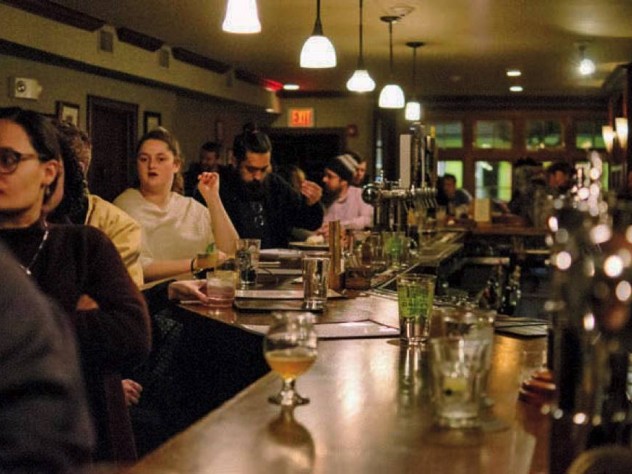 Guests sit along a long bar and face the stage