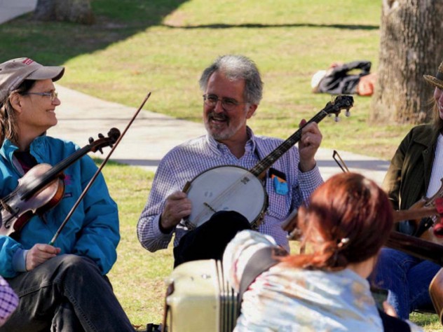 Two fiddlers and a banjo player take a break during an outdoor performance.