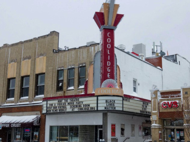 Photo of the exterior of Coolidge Corner Theater, with its vertical red neon sign.