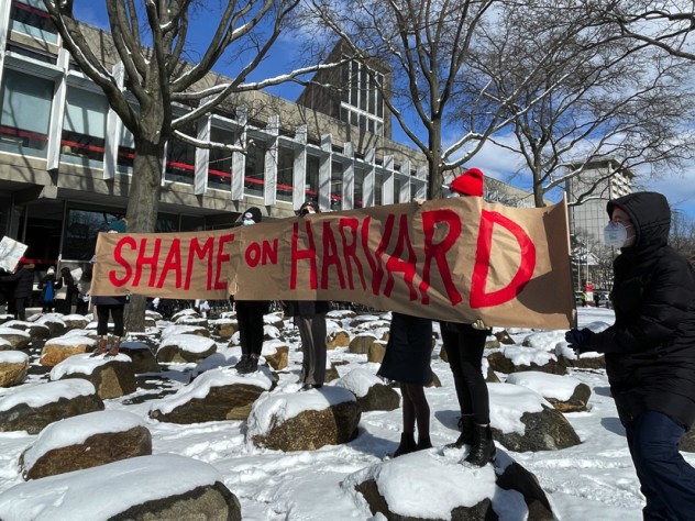 Demonstrators hold up a sign that reads, "Shame on Harvard."