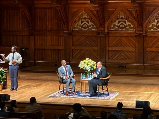 Martin Luther King III and Brandon Terry seated in chairs on a large auditorium stage