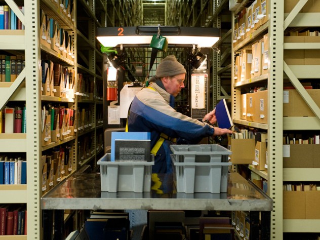Nearly half of Harvard’s collection is housed at the Harvard Depository, a marvel of efficient off-campus storage. Library assistant Carl Wood reshelves books in the 30-foot-high, 200-foot-long stacks.