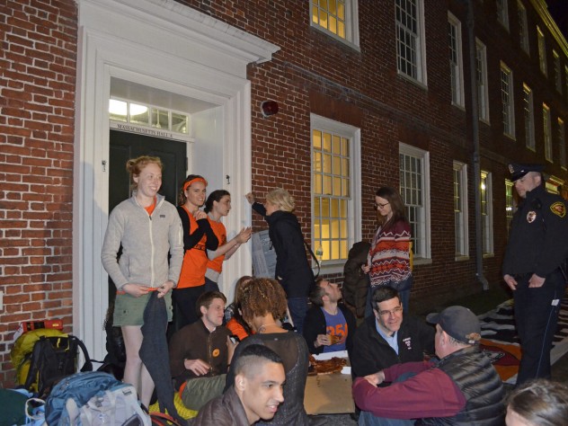 Students sit in front of an entryway to Mass. Hall, as Harvard University police look on.