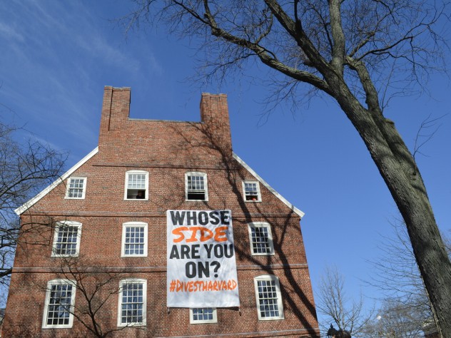 A Divest Harvard sign hangs from the windows of Mass. Hall.