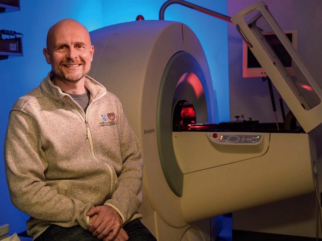 Matthias Nahrendorf seated in front of a PET/CT scanner