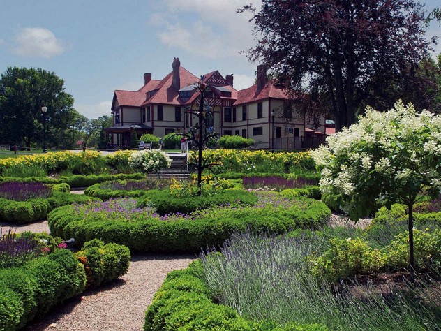 Wide view of formal gardens with a historic mansion in the background