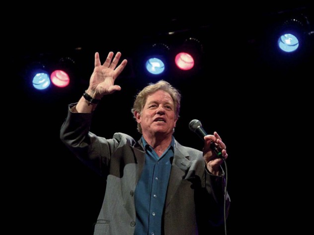 Jimmy Tingle holding a microphone and performing on stage 