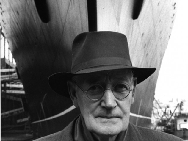 Wearing his trademark fedora, Gibbs stands in front of the SS <i>United States</i> at her Hudson River pier in 1955.
