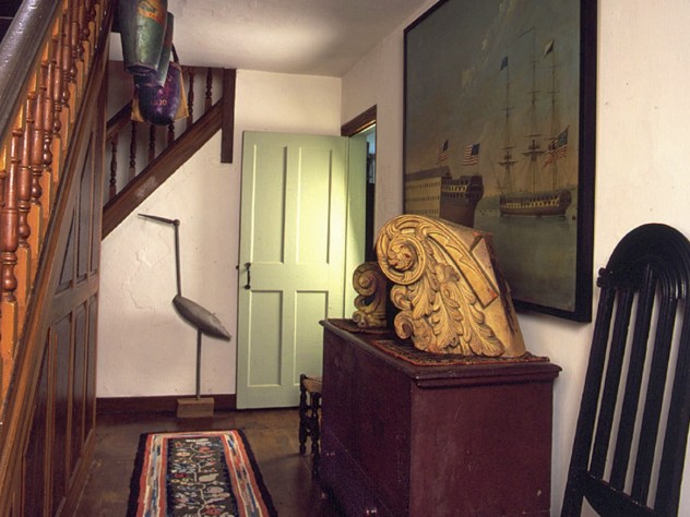 Photograph courtesy of Historic New England In the hallway, an 1814 oil painting depicts the launching of the U.S. frigate <i>Washington</i> at the Portsmouth, New Hampshire, Navy Yard. In the rear stands an ingenious 1907 carved crane decoy that folds up to fit into a hunter’s pack.