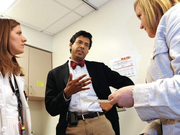Gawande speaks with patient Ericka Webb (right) at a post-surgical follow-up. Medical student Devon Quasha ’02, J.D. ’06, is at left..