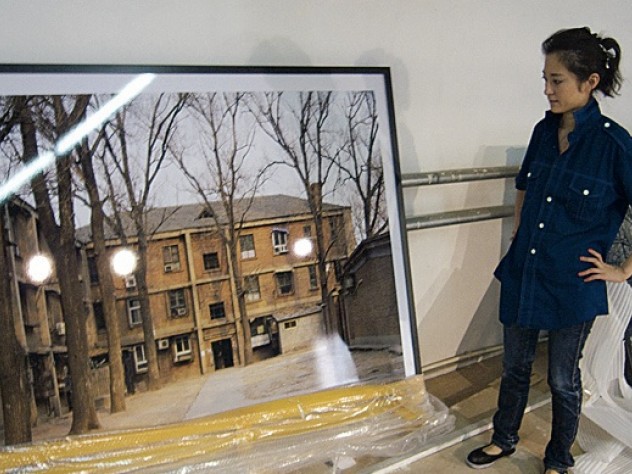 Graduate  student Ren Wei with one of Wang Di’s photographs  at a studio in Beijing. 