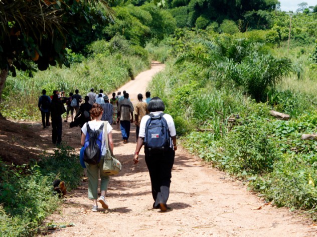 Photograph by Nur Ibrahim The students and a group of farmers walk along a road to a cacao farm in Bonsaaso district, a part of the UN Millennium Villages Project.