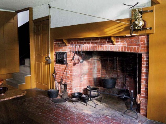 The main house kitchen, with a massive fireplace, and the narrow doorway to the service stairs.