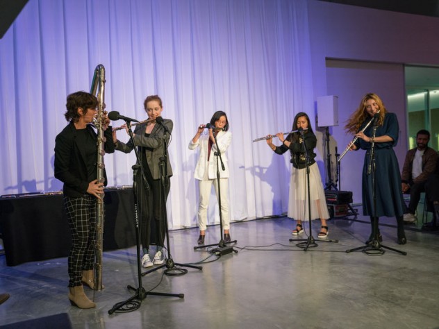 Five flutists playing together on stage