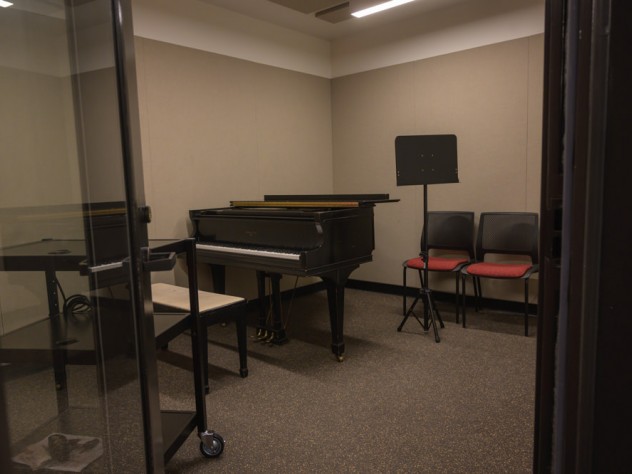 A music practice room with a piano and music stand