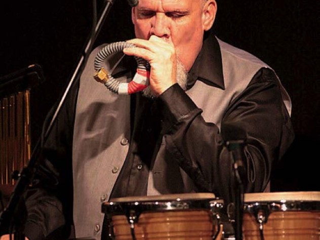 Percussionist Manolo Badrena playing a percussion instrument.