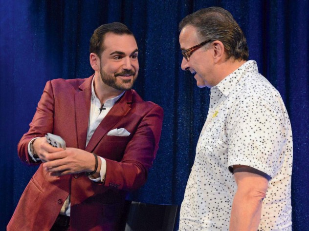 A magician and comedian doing a card trick with an audience member
