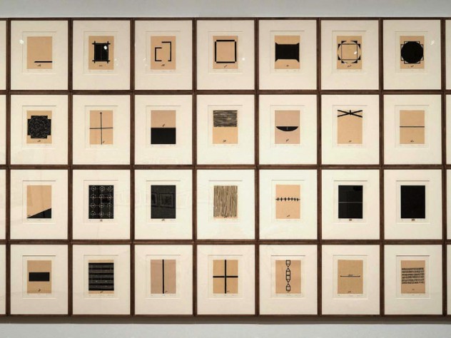 A grid of of 36 abstract black-and-white prints, each representing some aspect of the homes that artist Zarina has lived in, with Urdu and English inscriptions under each