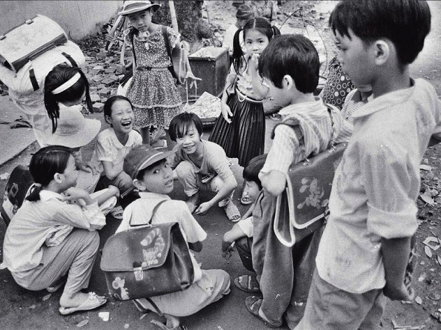 Black and white photo of a group of Vietnamese children, titled “Schoolchildren Playing Cards”