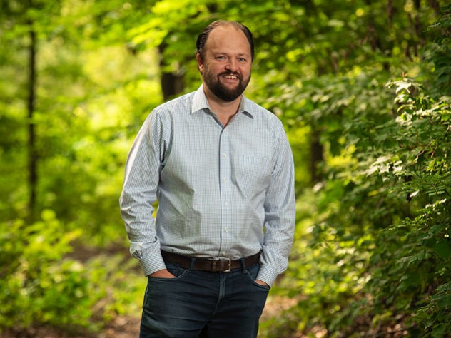 Ross Douthat standing in a wooded park