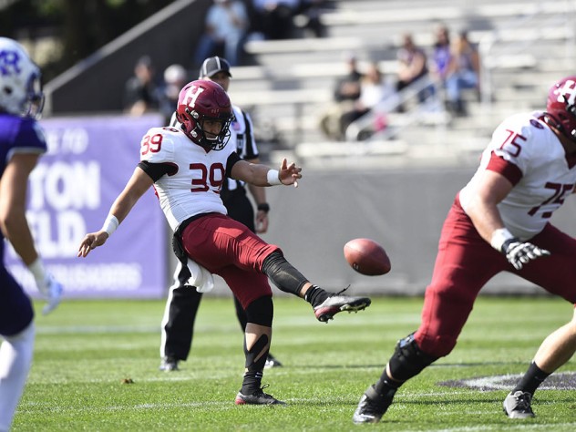 The Harvard punter kicks the football