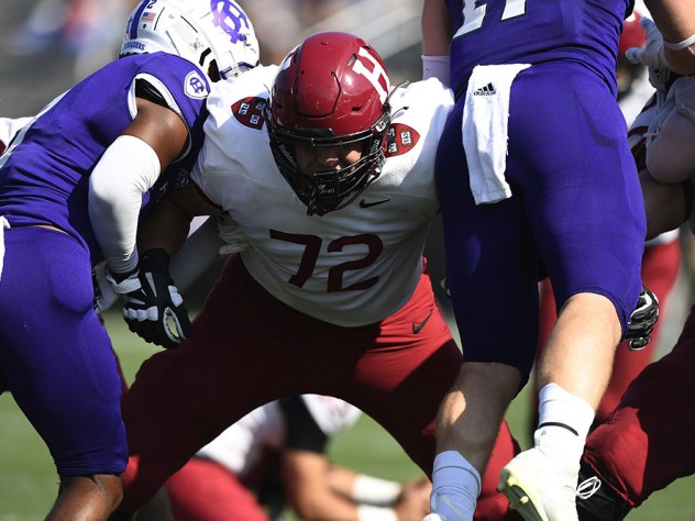A Harvard lineman holds back two Holy Cross defenders