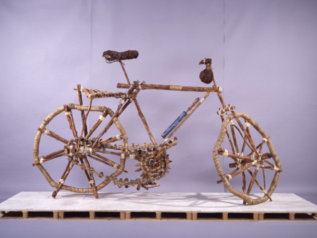 Photograph courtesy of the Cooper Gallery <i>Bicicleta rural/Rural Bicycle</i>, an eight-foot-tall wood and rope sculpture by Mozambique artist Titos Mabota, towers over the final room of the Cooper Gallery exhibit.