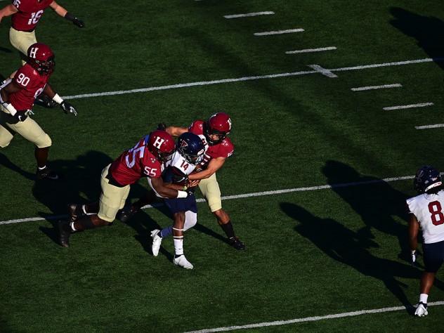 Two Harvard defenders tackle Penn's Maurcus McDaniel