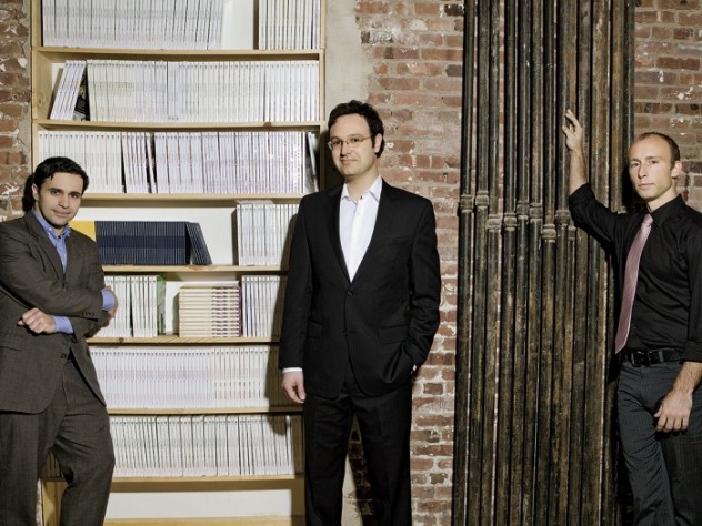 Editors with their product. Left to right, Keith Gessen, Mark Greif, and Chad Harbach of <i>n+1</i> at their Brooklyn office, with a bookcase full of past issues.