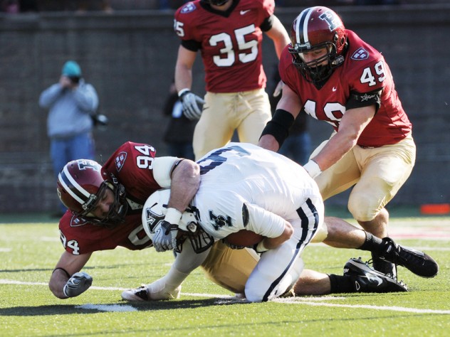 Photograph by Meredith Keffer Senior linebacker Nick Hasselberg (94) was in on 20 tackles, tying a single-game Harvard record set in 1999 by Isaiah Kacyvenski ’00. Above, he wraps up Eli wideout Cameron Sundquist after a four-yard pass reception in the opening period. Trailing the play is linebacker Alex Gedeon (49).