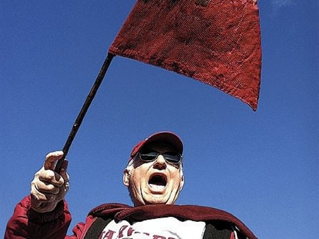 Photograph by Sara Bethell Bill Markus ’60 waving the Little Red Flag at Yale Bowl (see <a href="http://harvardmagazine.com/2003/09/superfan.html">“Superfan”</a>). Crimson loyalists have taken the flag to 124 Yale games since 1884; on Markus’s watch, Harvard is now 12-1.
