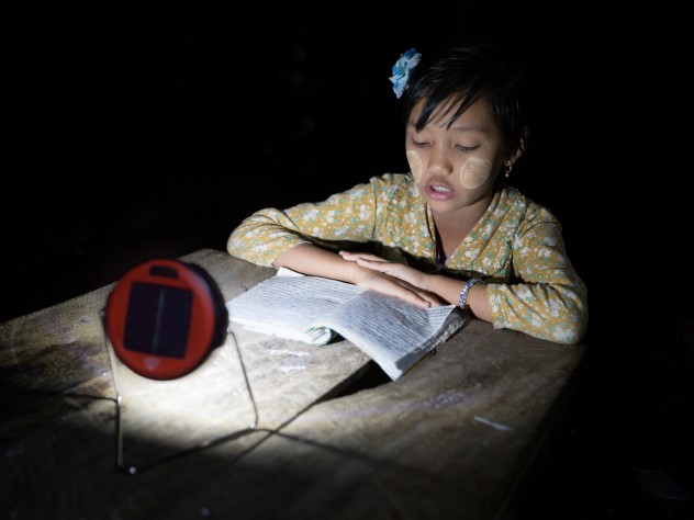  enabling reading, or homework, at night, in lieu of candles, which are expensive, a fire hazard in bamboo houses, and unsuitable for use under mosquito netting. (The white paste on the girl’s cheeks is <i>thanaka,</i> a cosmetic paste made from ground bark, which many women and girls in Myanmar apply to guard against sunburn and to protect the skin.)