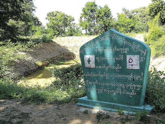 Photograph by John Rosenberg Hundreds of miles north of the delta, farmers in Myanmar’s Dry Zone, like these in Kangyikone village, grow peanuts as a cash crop—and rely on oxen for power. Proximity advisers are introducing practices like “green manure” plantings to enrich the soil. The sign details an infrastructure-aid project, managed by Proximity, to restore the village’s drinking-water pond.