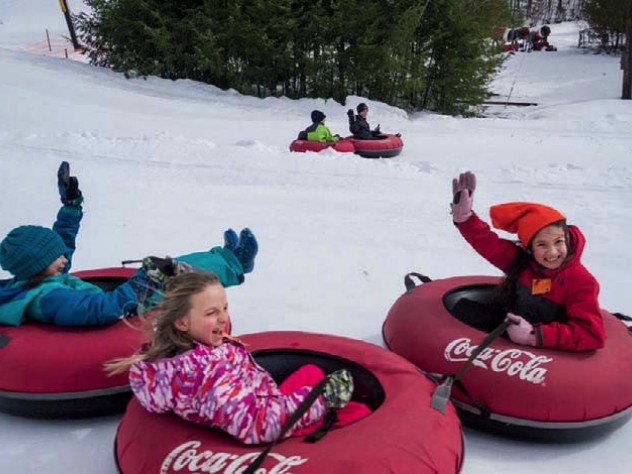 Kids in snow suits having fun snow-tubing