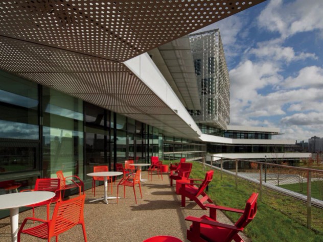 A photo of red chairs and white tables on one of the south-facing terraces afford views of Boston and Cambridge.