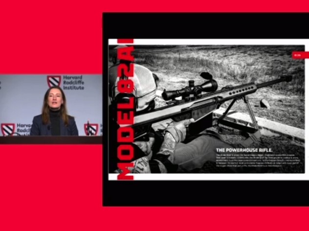 A woman speaking at a podium, with an image of a high-power rifle projected beside her